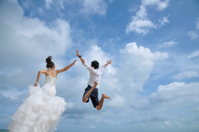空に向かったジャンプをする新郎新婦